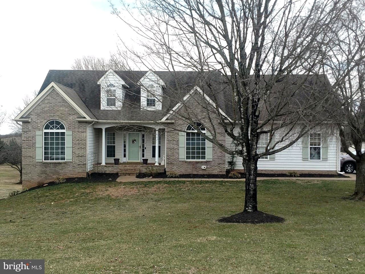 The same Cape Cod-style home in Culpeper, VA before its roof replacement, with brick and white siding, two dormers, red shutters, a covered front porch, the old weathered roof, and a listing watermark in the lower left
