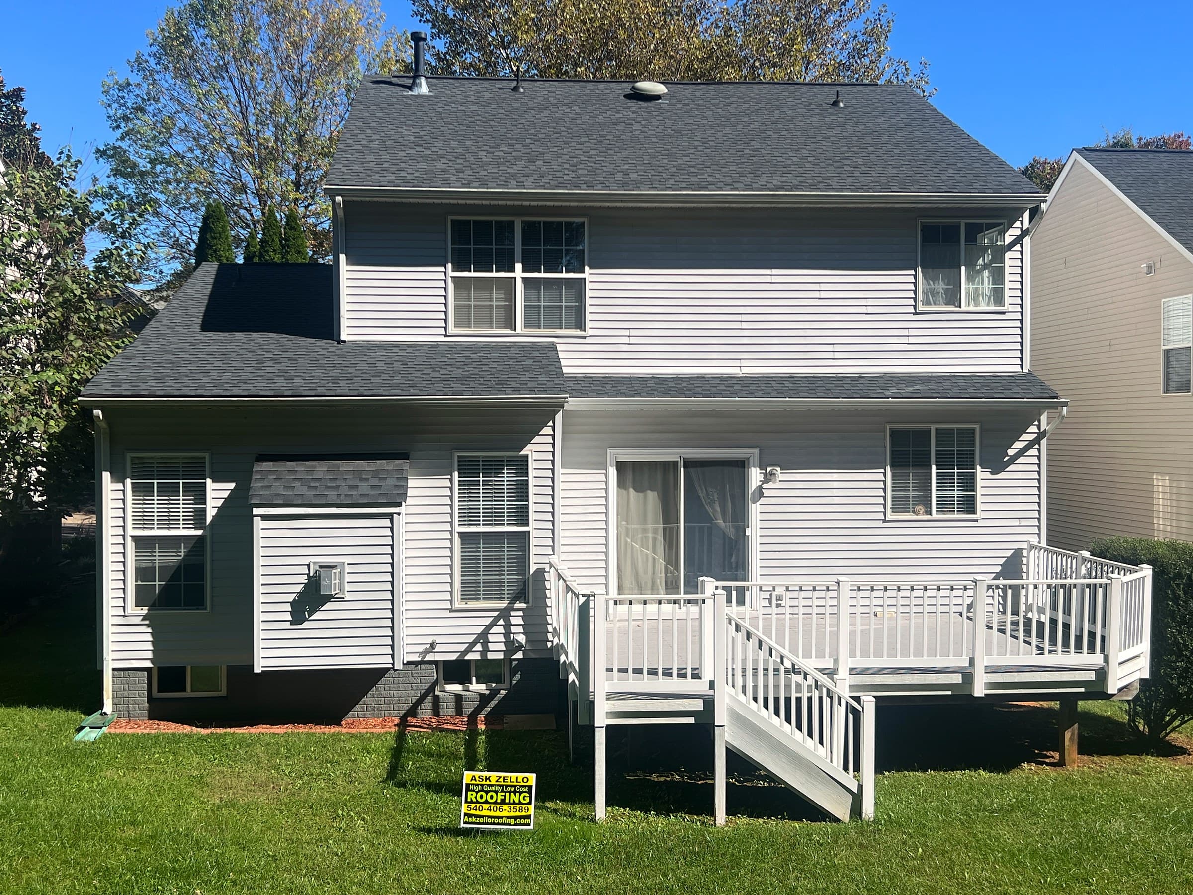 Back of a two-story home in Culpeper, VA with gray siding, a white deck with stairs, a GAF Timberline HDZ Charcoal roof, and an Ask Zello Roofing yard sign on the lawn