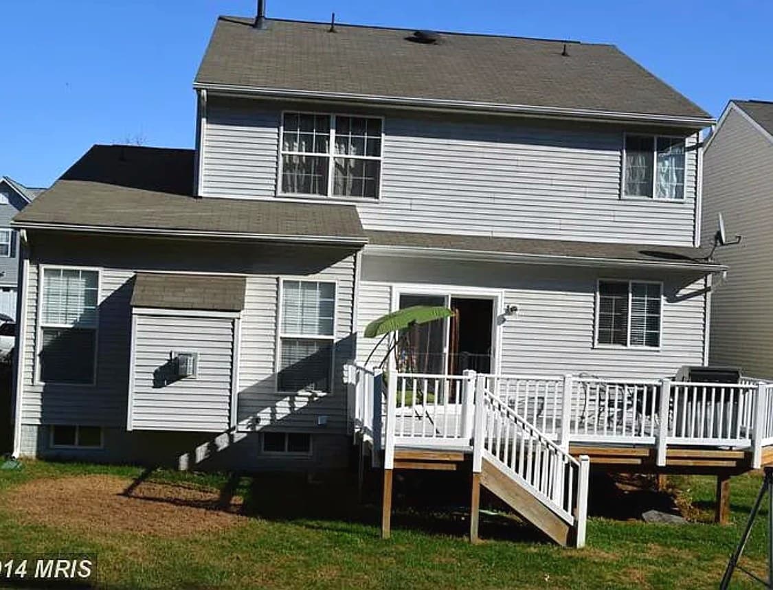 Back of the same Culpeper, VA home before its roof replacement, with the old roof, a white deck, and a listing watermark in the lower left