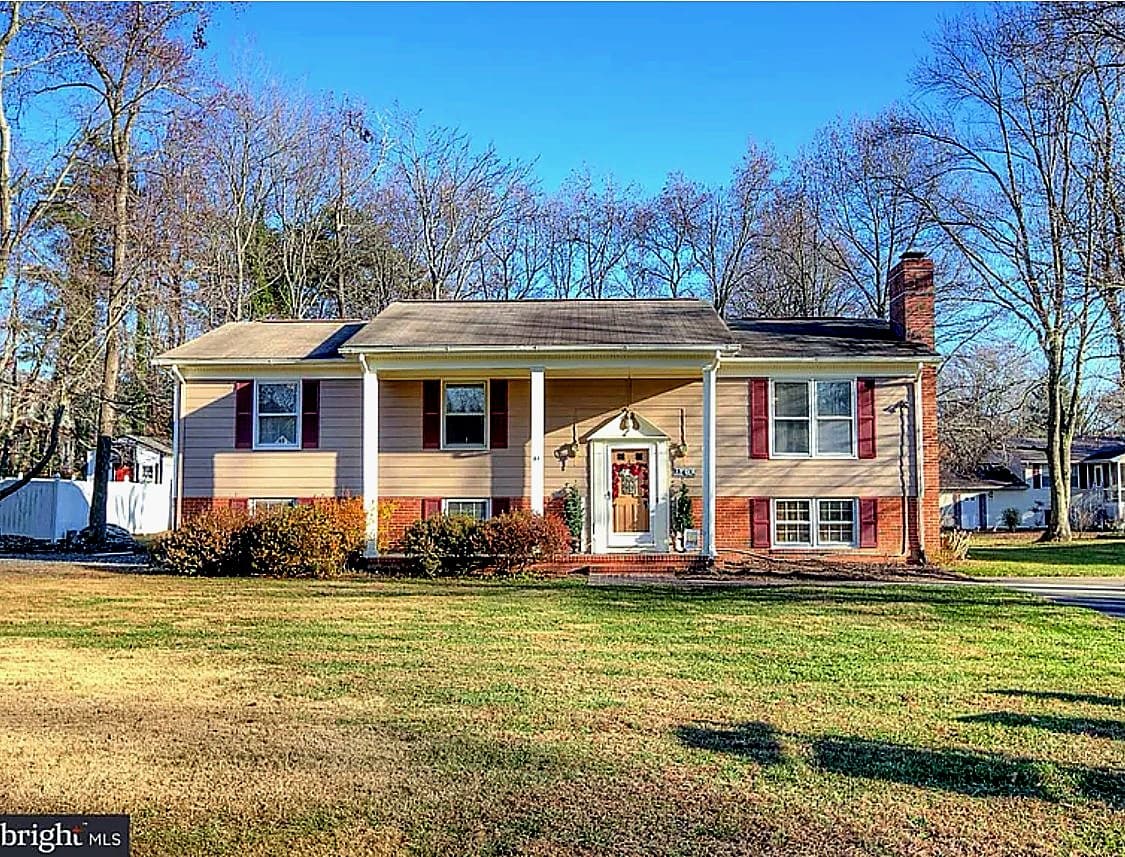 Before roof replacement on a split-foyer home in the Fredericksburg mailing area of Stafford County, with cream siding, a brick lower level, and the old roof.
