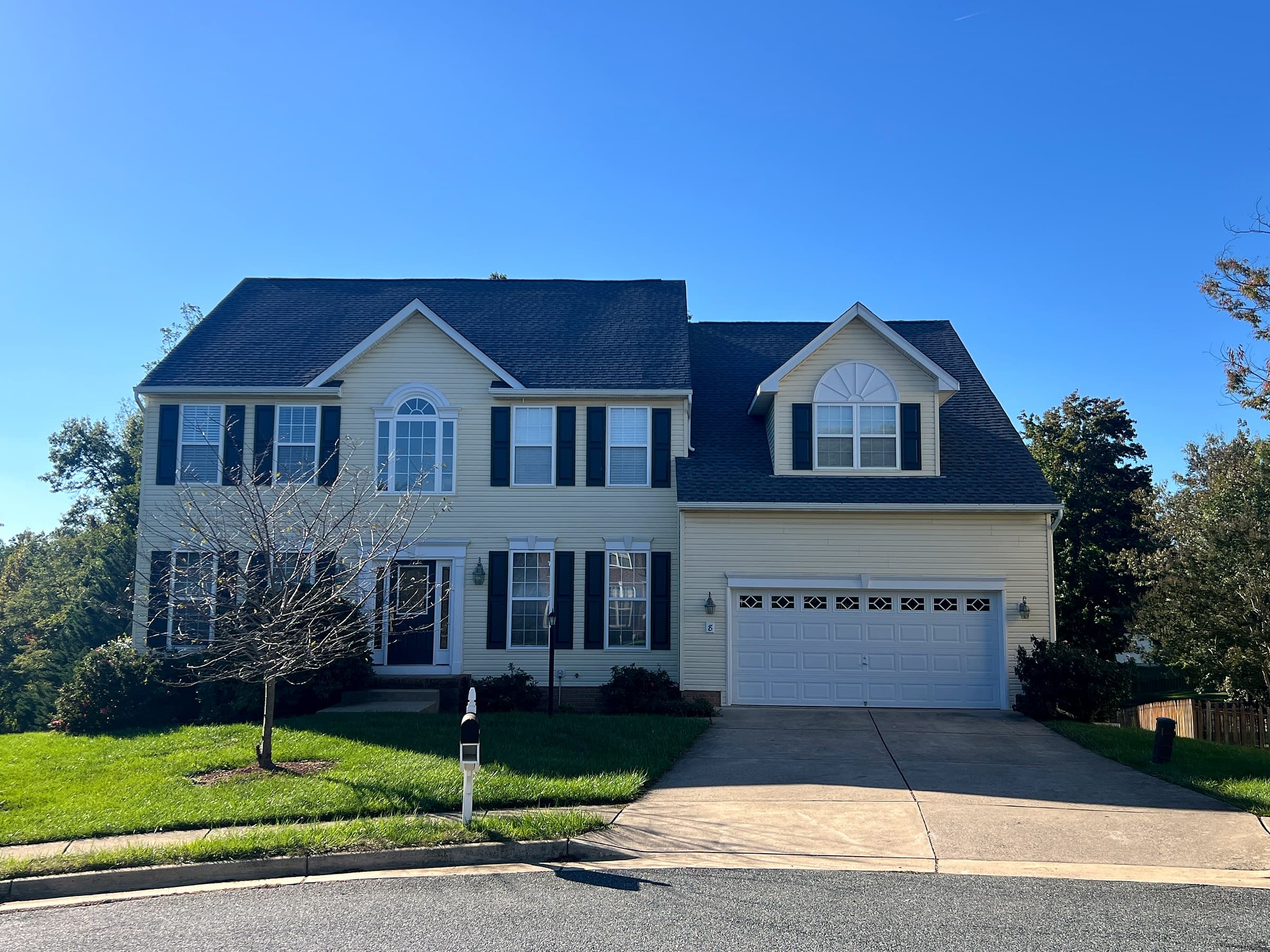 Two-story yellow colonial in Leeland Station, Stafford County, with black shutters, a two-car garage, and a new GAF Timberline HDZ Pewter Gray roof.