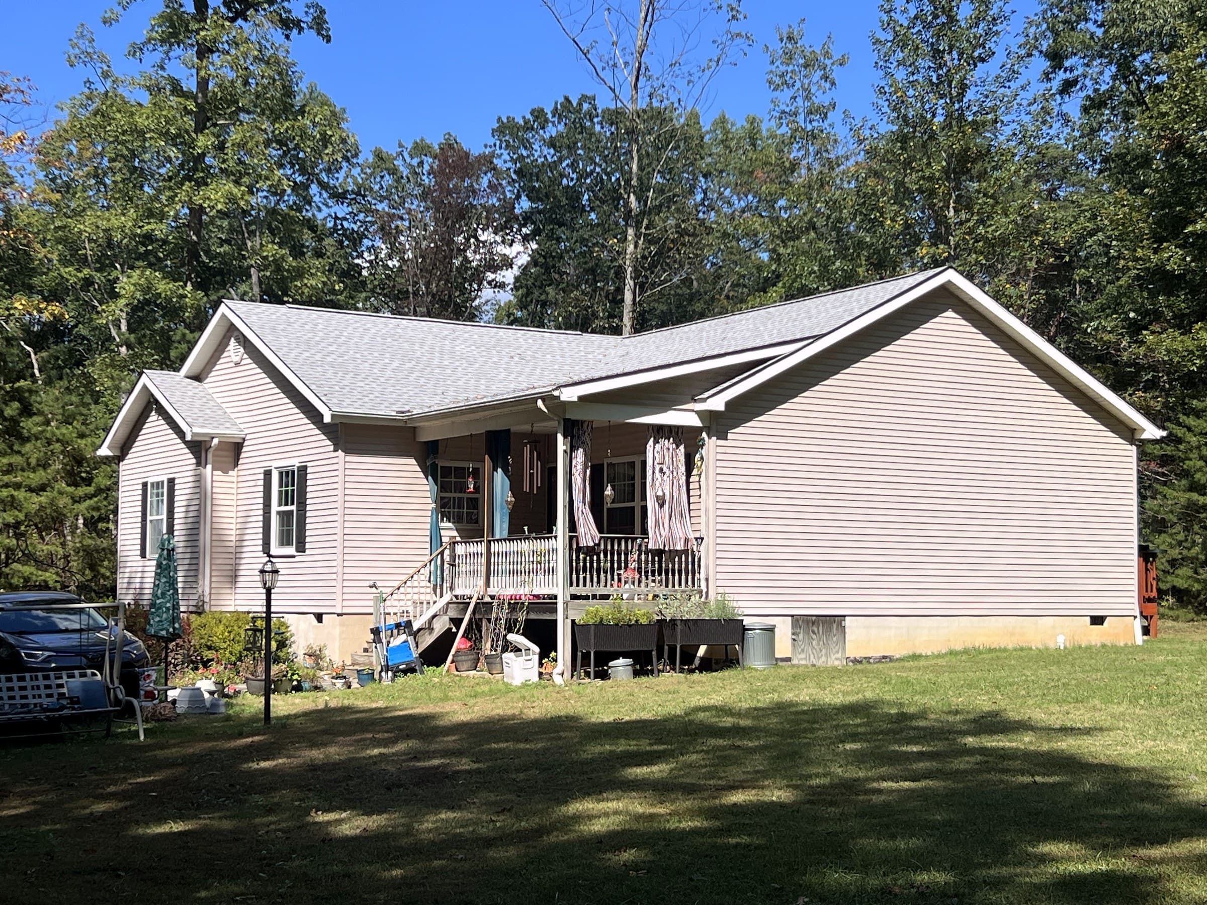 White ranch home in Rhoadesville, VA with a new GAF Timberline HDZ Fox Hollow Gray roof, red shutters, and a covered front porch