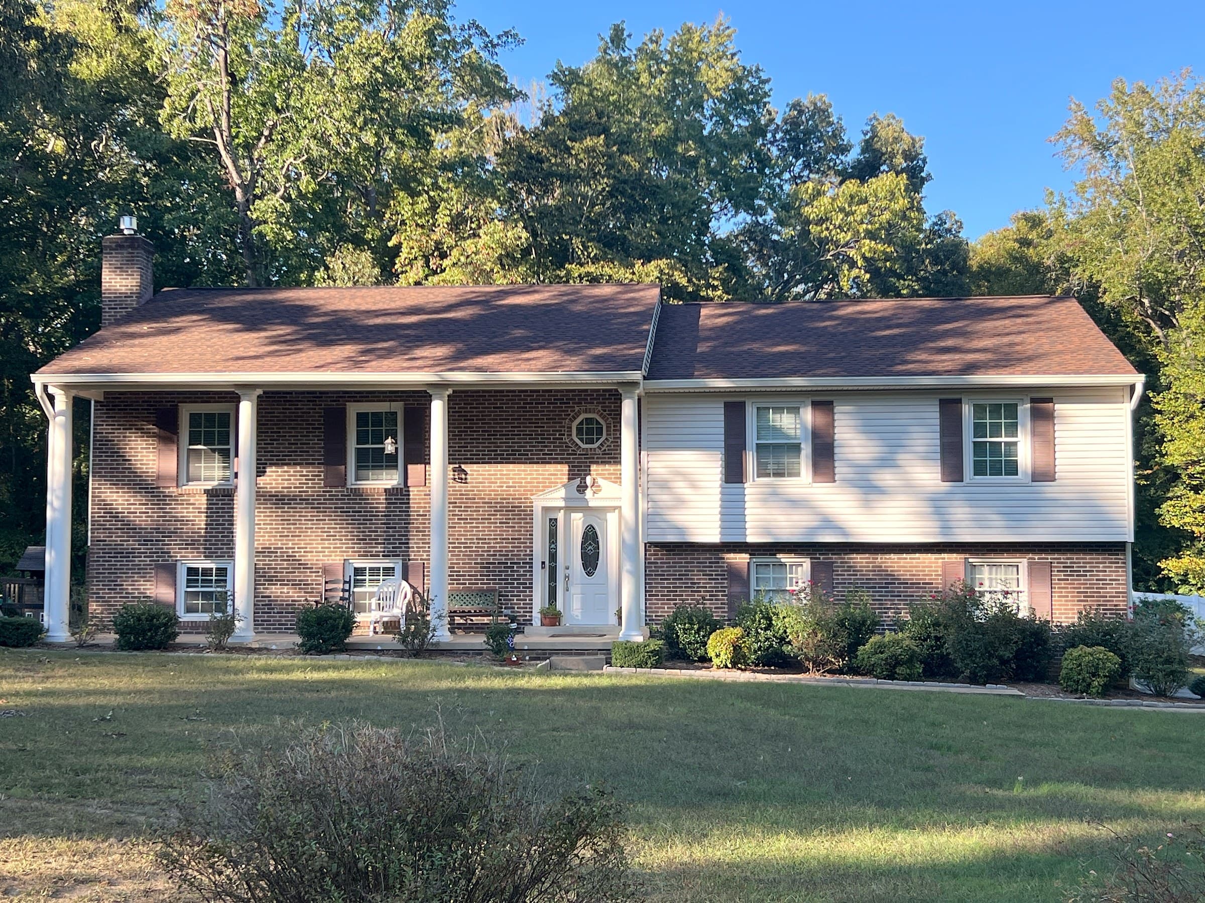 Split-level home in Stafford, Stafford County, with brick and white siding, a covered porch with white columns, and a new GAF Timberline HDZ Hickory roof.