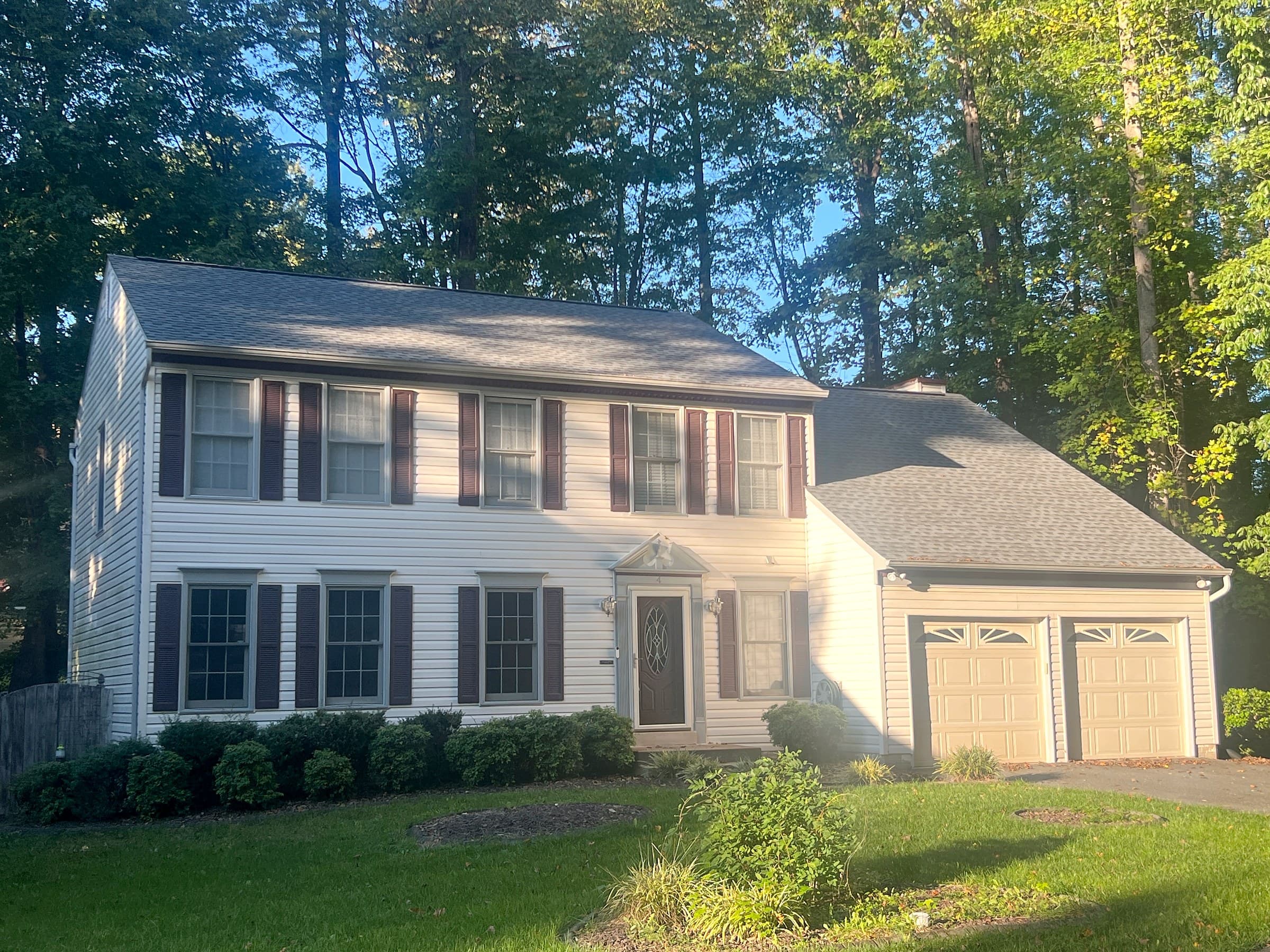 Two-story white colonial in Stafford, Stafford County, with dark shutters, a two-car garage, tall trees, and a new GAF Timberline HDZ Pewter Gray roof.