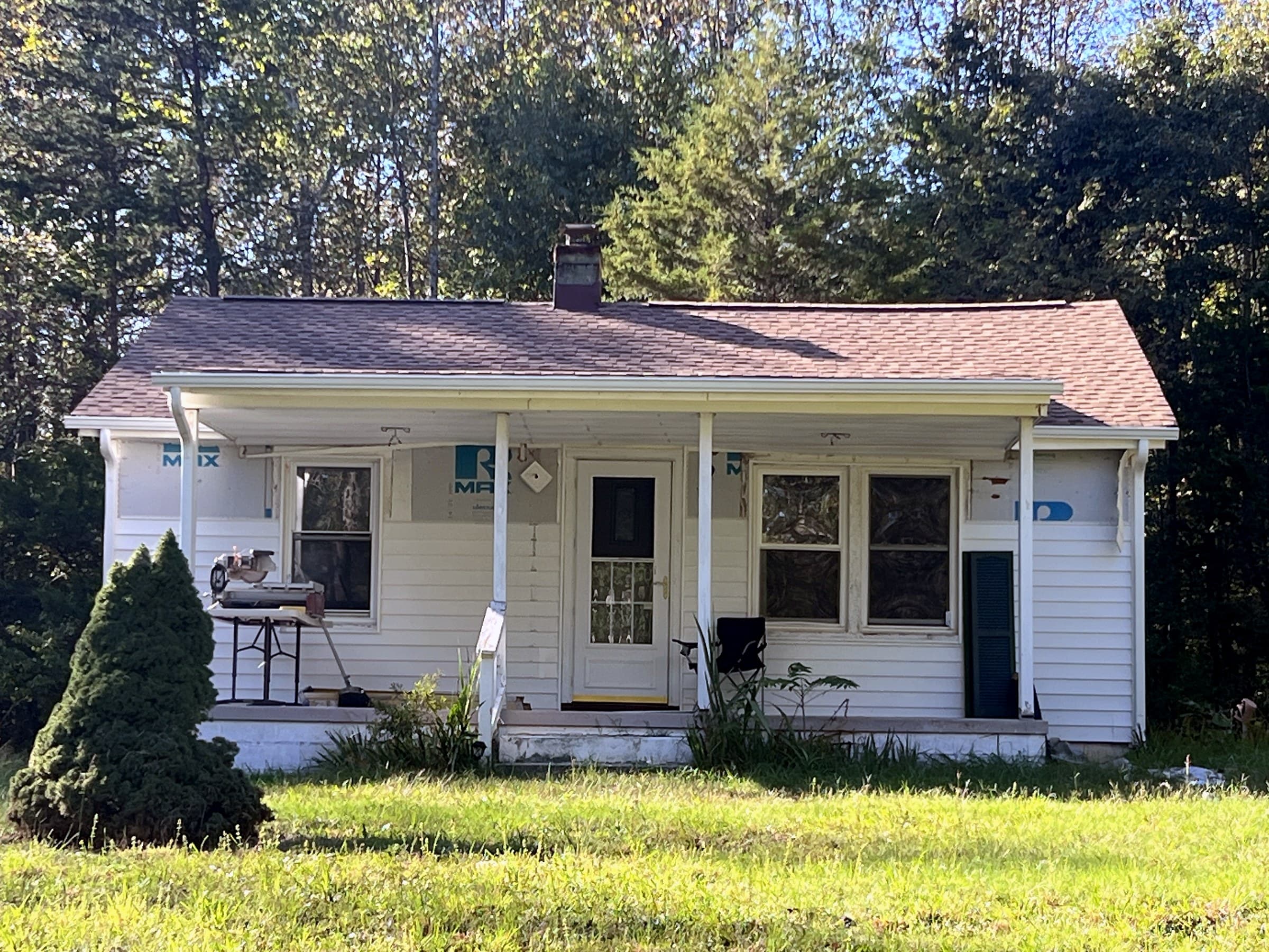 Small cottage in Unionville, VA with a completed GAF Timberline HDZ Shakewood roof, blue house wrap on the walls, and tools on the porch