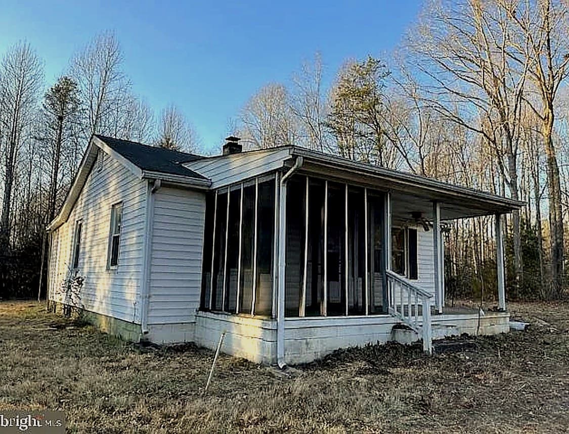 Small cottage in Unionville, VA with an older dark asphalt roof, light siding, a front porch, and a realtor watermark in the corner