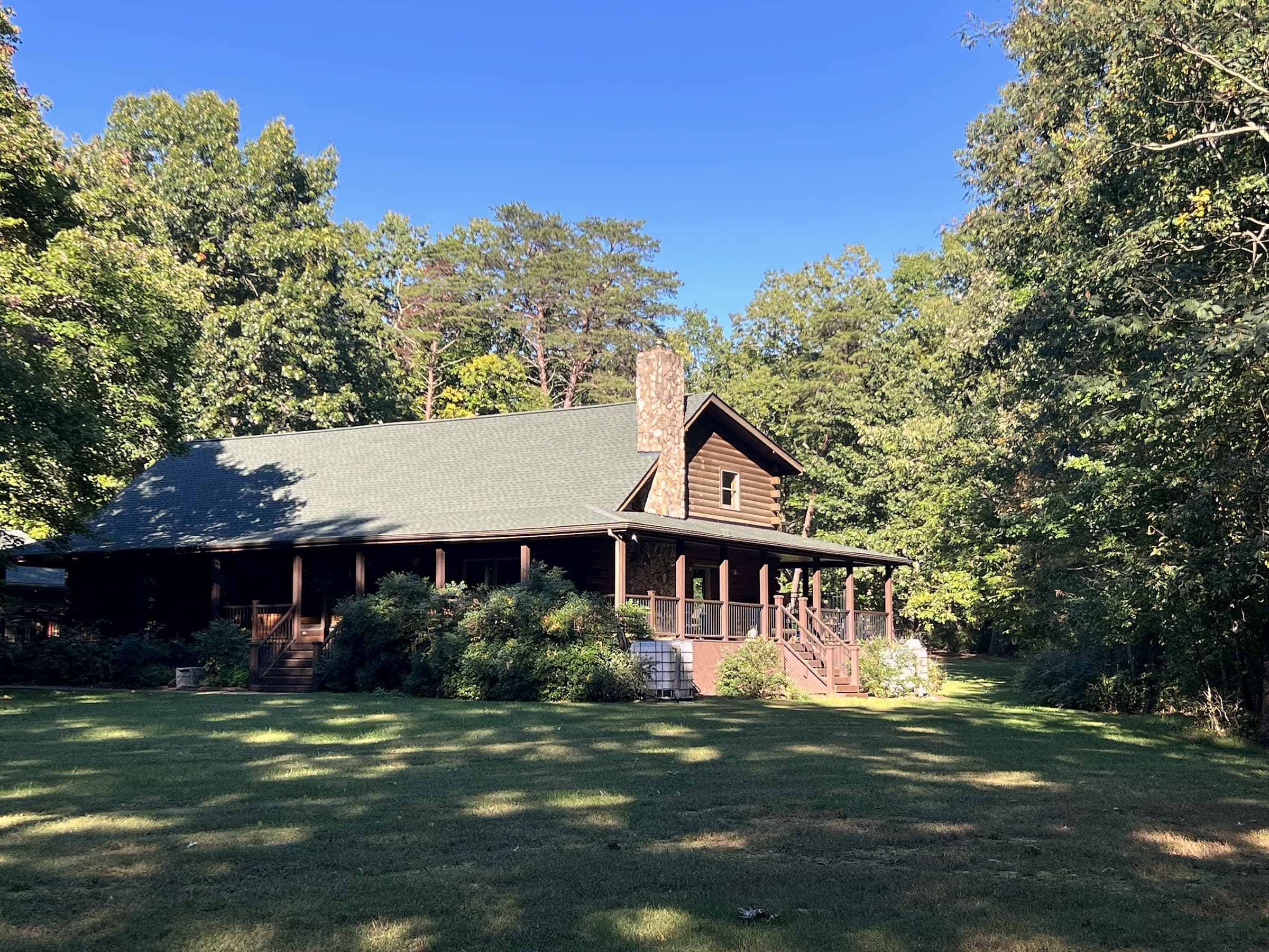 Log home in Unionville, VA with a new GAF Timberline HDZ Hunter Green roof, a stone chimney, and a covered porch