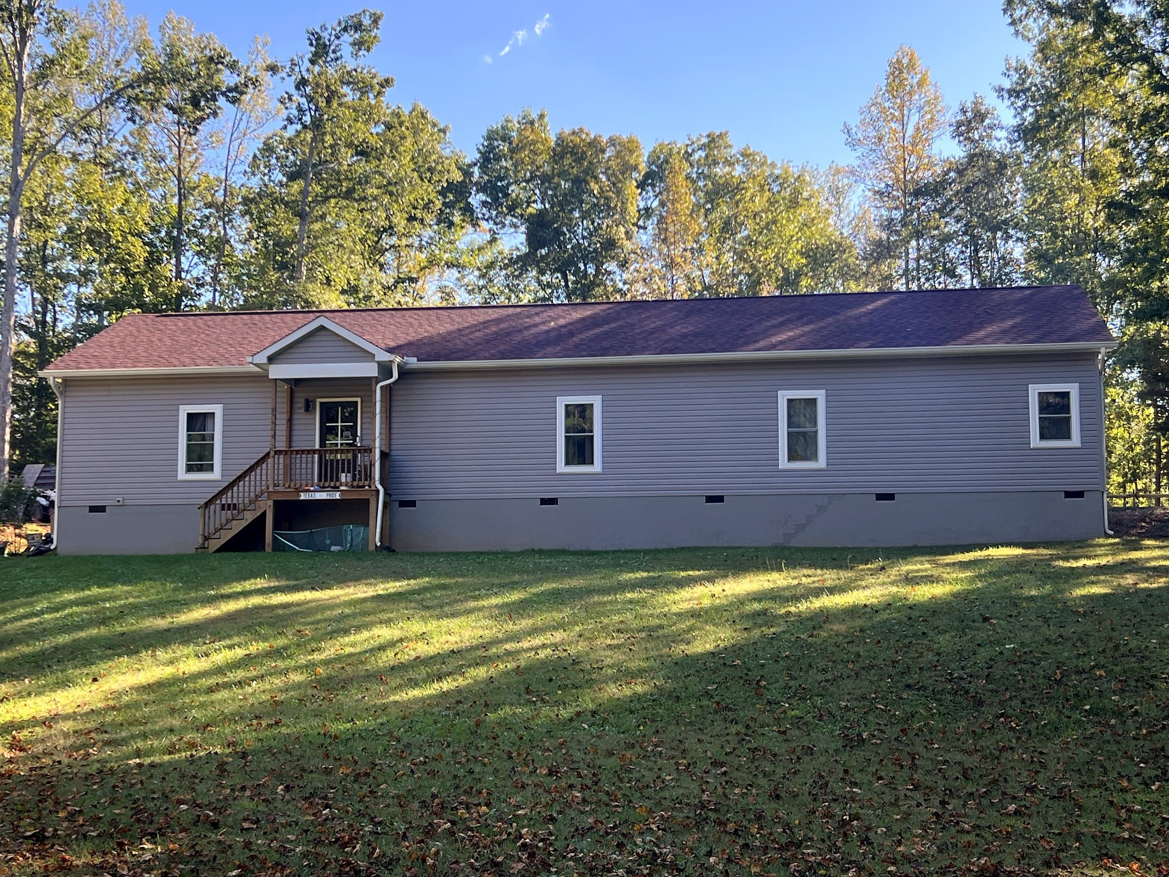 Ranch home in Unionville, VA with light gray siding, white windows, a wooden front porch with steps, and a new GAF Timberline HDZ roof in Hickory.